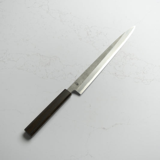 Sakai Kikumori Kikuzuki Rin Yanagiba 270mm – Hand-forged carbon steel sushi knife with ebony handle, crafted in Sakai, Japan. Available at Blade & Board.
